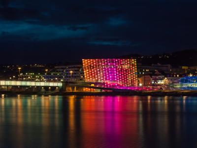 Ars Electronica Center illuminated at night on the Danube riverbank in Linz