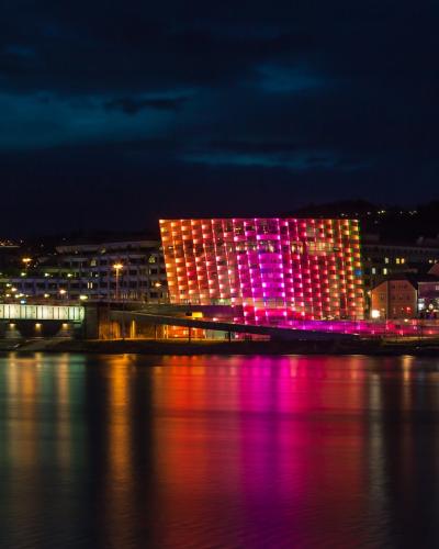 Ars Electronica Center illuminated at night on the Danube riverbank in Linz