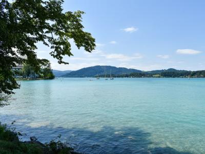 Calm turquoise Austrian lake with sailboats and low wooded hills under a summer sky