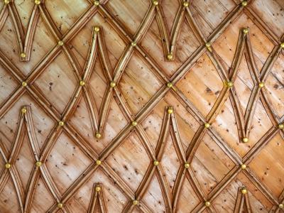 A close-up view of an ornate wooden ceiling featuring a geometric lattice pattern of wooden beams with gold-colored spherical finials at the intersections, and the date "1515" inscribed near the bottom.