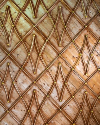 A close-up view of an ornate wooden ceiling featuring a geometric lattice pattern of wooden beams with gold-colored spherical finials at the intersections, and the date "1515" inscribed near the bottom.