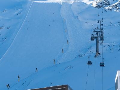 A snowy mountain ski slope with chairlifts and a modern station building in the foreground, featuring a vertical sign reading "SCHWARZE SCHNEIDE".