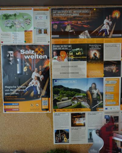 A corkboard display featuring a large poster for "Salzwelten Salzburg" alongside a map of the Hallein salt mine, informational brochures, and a grid of staff photos.