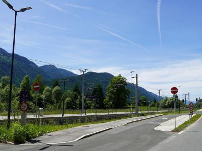A view of a railway station platform and adjacent road with mountains in the background, featuring a purple station sign reading "St. Stefan-Vorderberg" and a "P+R" parking sign.