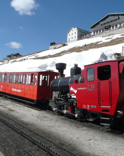 Red SchafbergBahn cog railway train at the Schafberg summit station above St. Wolfgang
