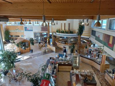 An interior view of a spacious, wood-paneled visitor center or cafeteria featuring a curved service counter, dining tables, and a sign reading "Nationalpark Stube".