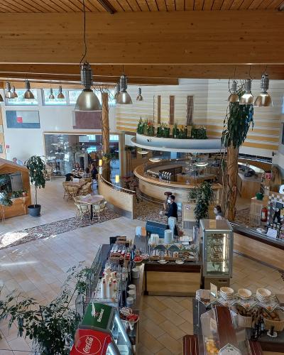 An interior view of a spacious, wood-paneled visitor center or cafeteria featuring a curved service counter, dining tables, and a sign reading "Nationalpark Stube".