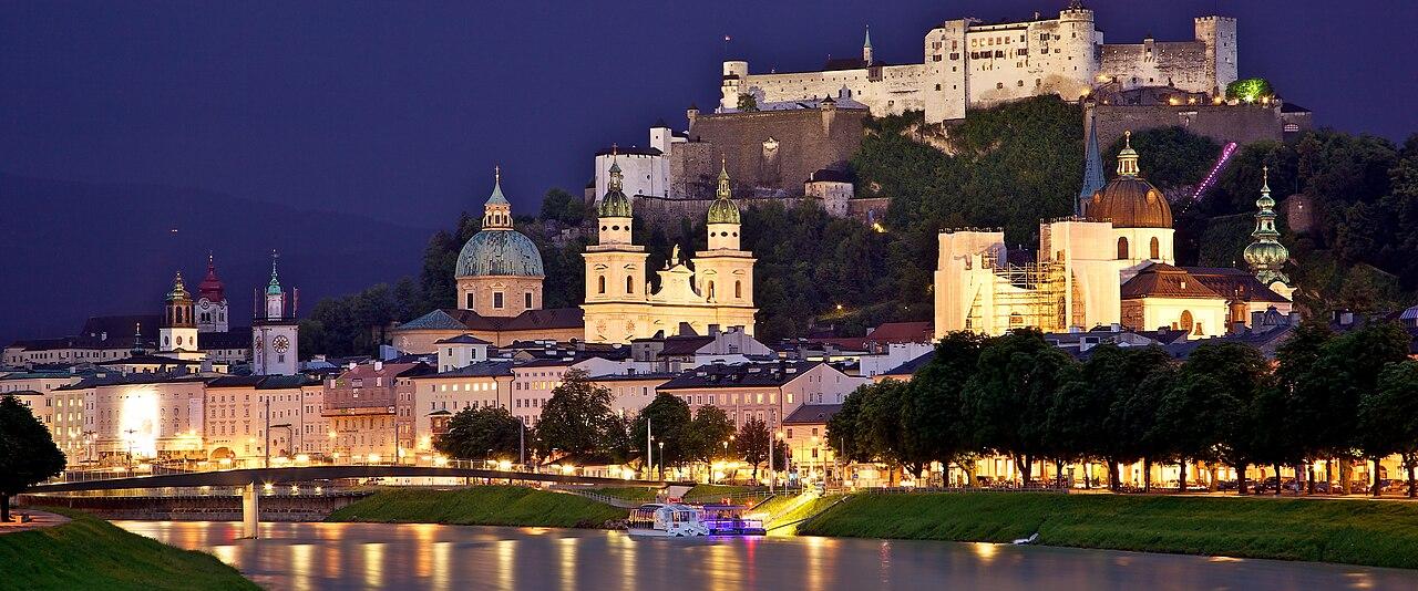 Salzburg's old town and Hohensalzburg Fortress lit at dusk across the Salzach