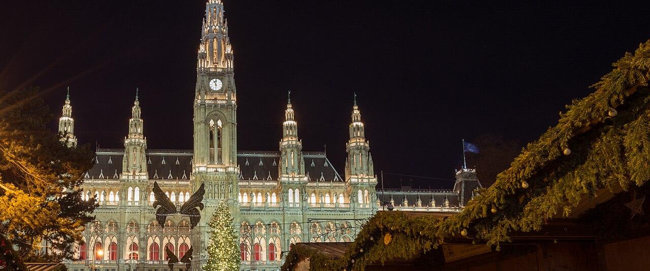 The Wiener Christkindlmarkt on Rathausplatz at night, with the illuminated neo-Gothic City Hall behind the market stalls