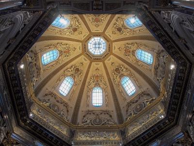 An ornate, octagonal dome ceiling with gilded stucco decorations, frescoes, and multiple arched windows, viewed from below.