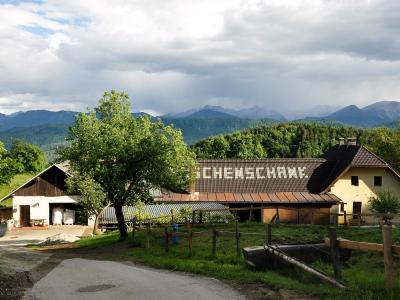 Carinthian farm with Buschenschank lettering on its roof and mountains rising in the distance