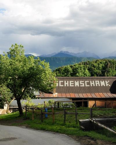 Carinthian farm with Buschenschank lettering on its roof and mountains rising in the distance