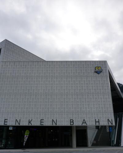 The image shows the modern, angular facade of a cable car station building with large lettering reading "PENKENBAHN" across the front and a logo for "Mayrhofen" on the upper right side.