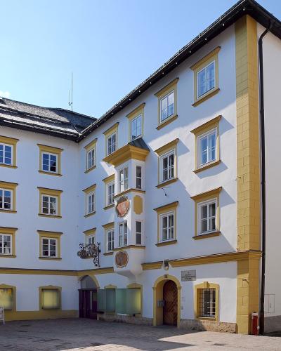 A white and yellow historic building with a courtyard, featuring a coat of arms and text on the wall, identified by the filename as 'Museum Kitzbühel, Hinterstadt 32'.