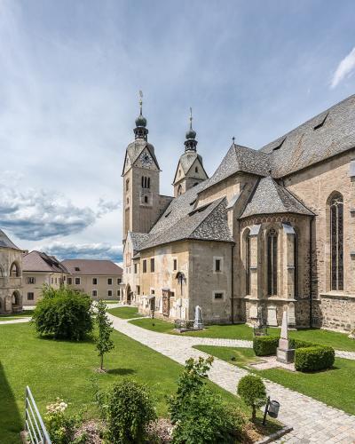 A large stone church with two onion-domed towers and an adjacent octagonal ossuary (charnel house) set within a grassy courtyard under a cloudy sky.