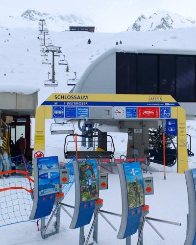 A ski lift station in a snowy mountain setting, featuring signage for the "Schlossalm" and "Weitmoser" lifts within the "Gastein" ski area.