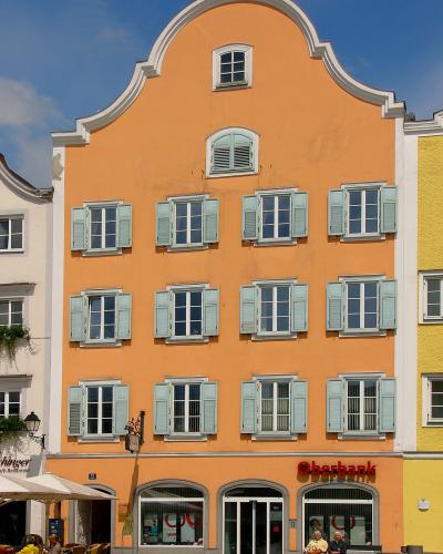A tall, orange-colored historic building with a stepped gable facade, light blue shutters, and an "Oberbank" branch on the ground floor, located at street number 12.