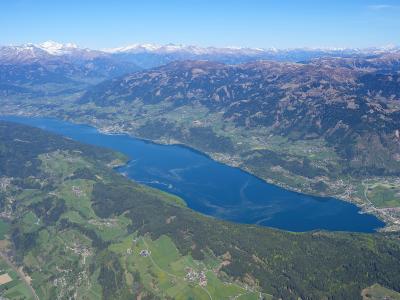 Aerial view of Lake Millstaettersee with snow-capped Alps behind, Carinthia