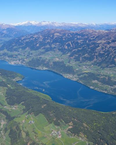 Aerial view of Lake Millstaettersee with snow-capped Alps behind, Carinthia