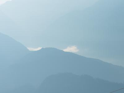 A cable car (gondola) suspended on cables against a backdrop of layered, hazy blue mountain ranges.