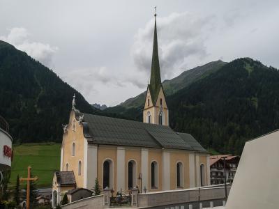 The Catholic parish church of St. Nicholas in the centre of Ischgl, with village houses and the Paznaun valley slopes behind