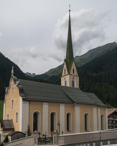 The Catholic parish church of St. Nicholas in the centre of Ischgl, with village houses and the Paznaun valley slopes behind