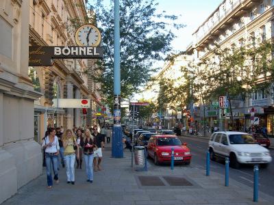 The image shows a busy urban shopping street in Vienna, featuring pedestrians, parked cars, and storefronts including a prominent "BÖHNEL" sign and a "Turek" sign.