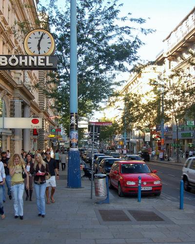 The image shows a busy urban shopping street in Vienna, featuring pedestrians, parked cars, and storefronts including a prominent "BÖHNEL" sign and a "Turek" sign.