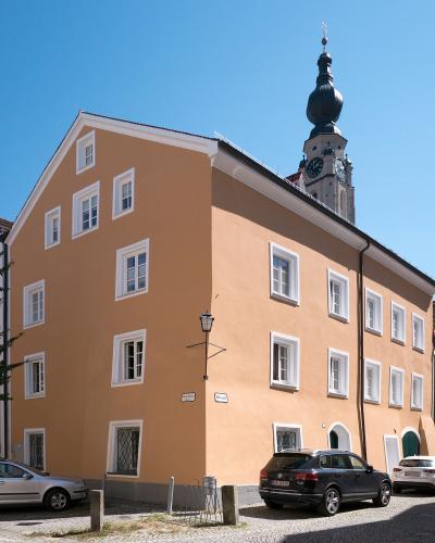 A large, peach-colored building with white-framed windows stands on a cobblestone street corner, with a church tower featuring a dark onion dome visible behind it.