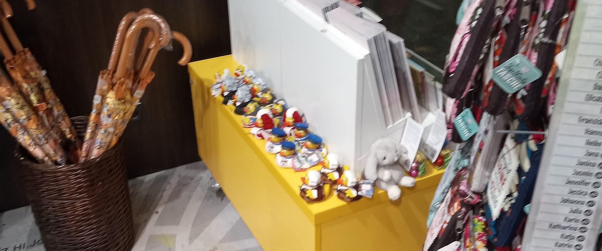 The image shows the interior of a souvenir or gift shop with merchandise like magnets, umbrellas, and plush toys, and a floor decal featuring a map of Vienna with street names like "Prater," "Untere Donaustraße," and "Aspernbrücke."