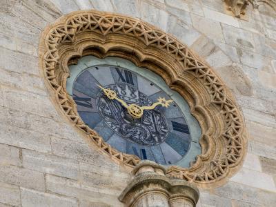 A close-up view of the ornate, Gothic-style astronomical clock face set into the stone facade of a large cathedral.
