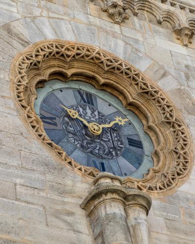 A close-up view of the ornate, Gothic-style astronomical clock face set into the stone facade of a large cathedral.