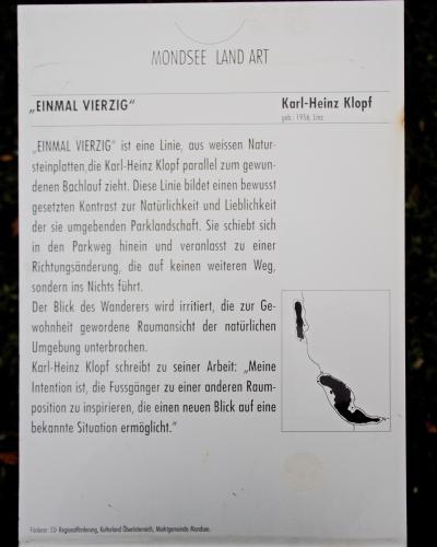A close-up photograph of an informational sign for a land art installation titled "EINMAL VIERZIG" by Karl-Heinz Klopff, part of the "MONDSEE LAND ART" series.